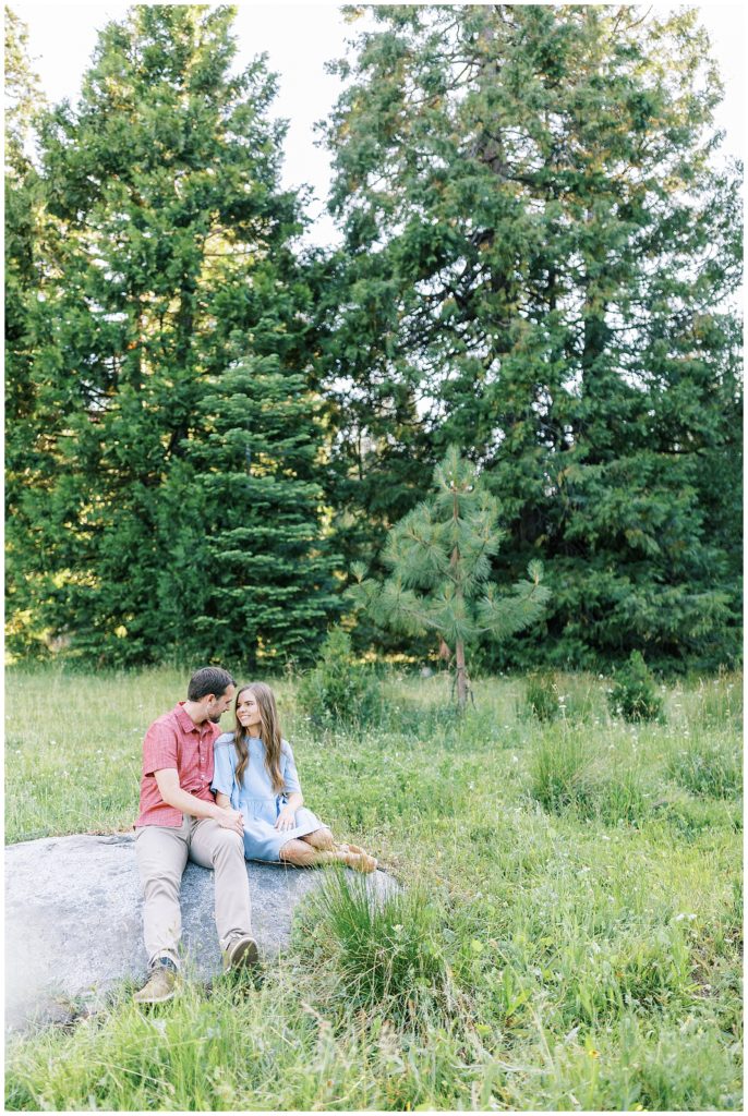 couple sitting on rock in mountain meadow