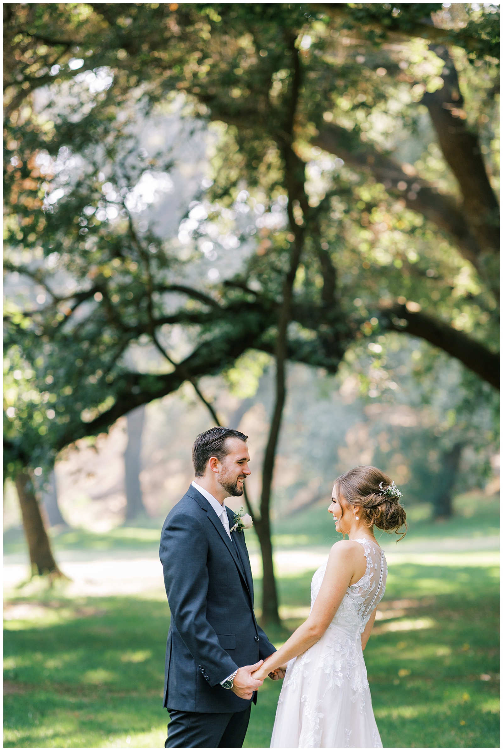 bride and groom holding hands smiling during first look outdoors under oak trees
