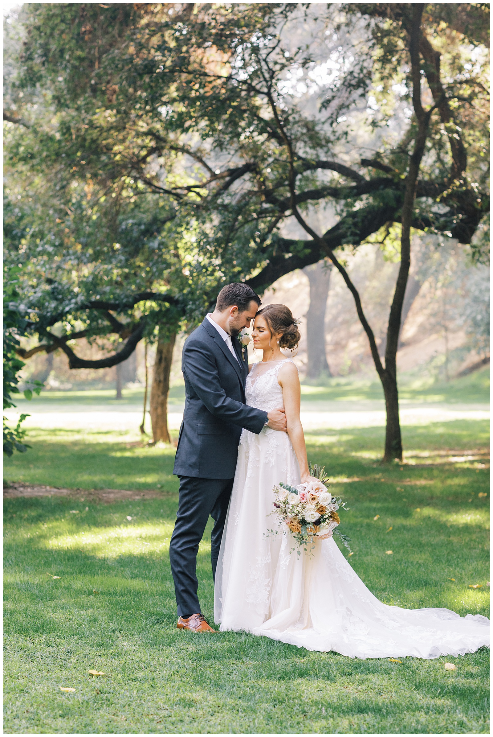 intimate image bride and groom embracing under oak trees
