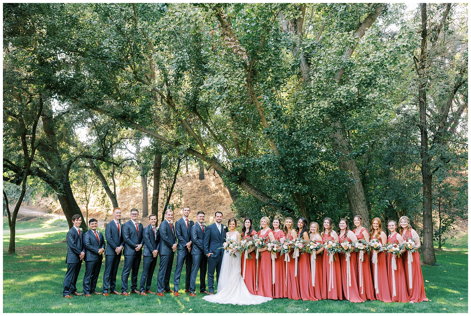 rust and grey bridal party photo outdoors under oak trees