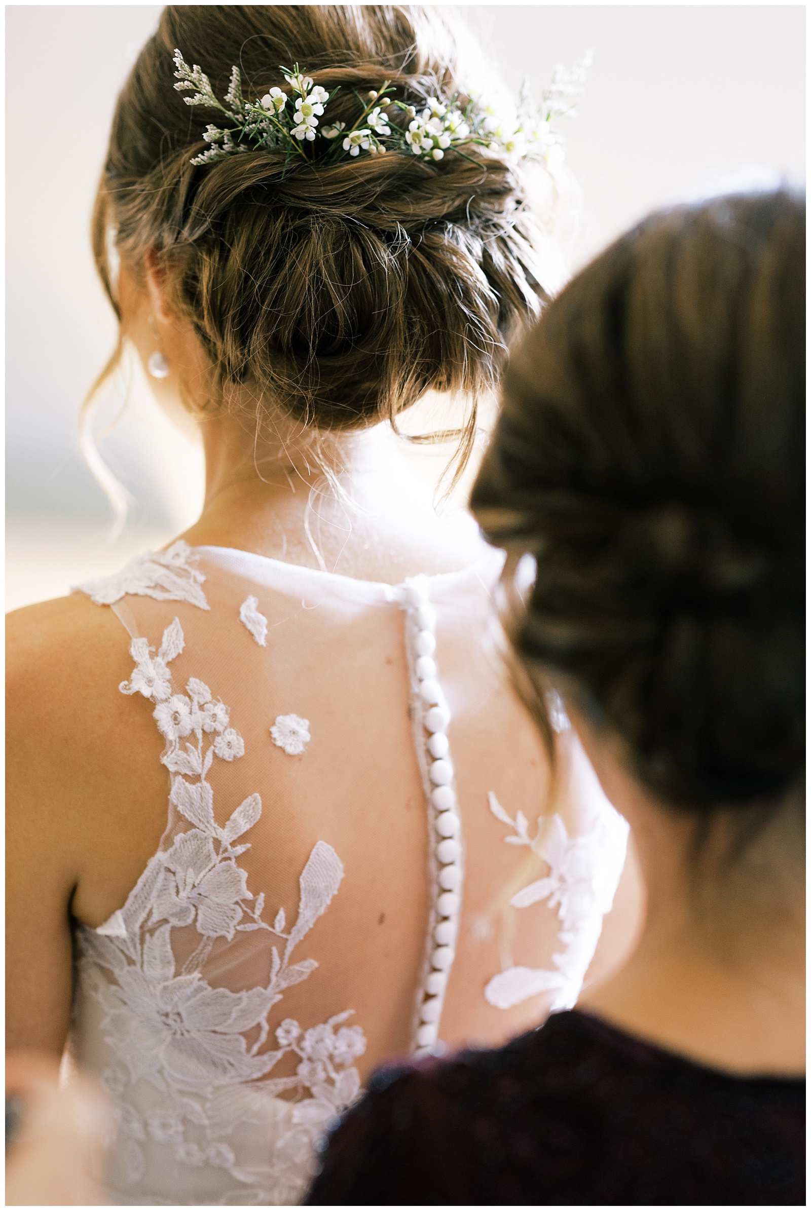 brides mom buttoning lace back wedding dress