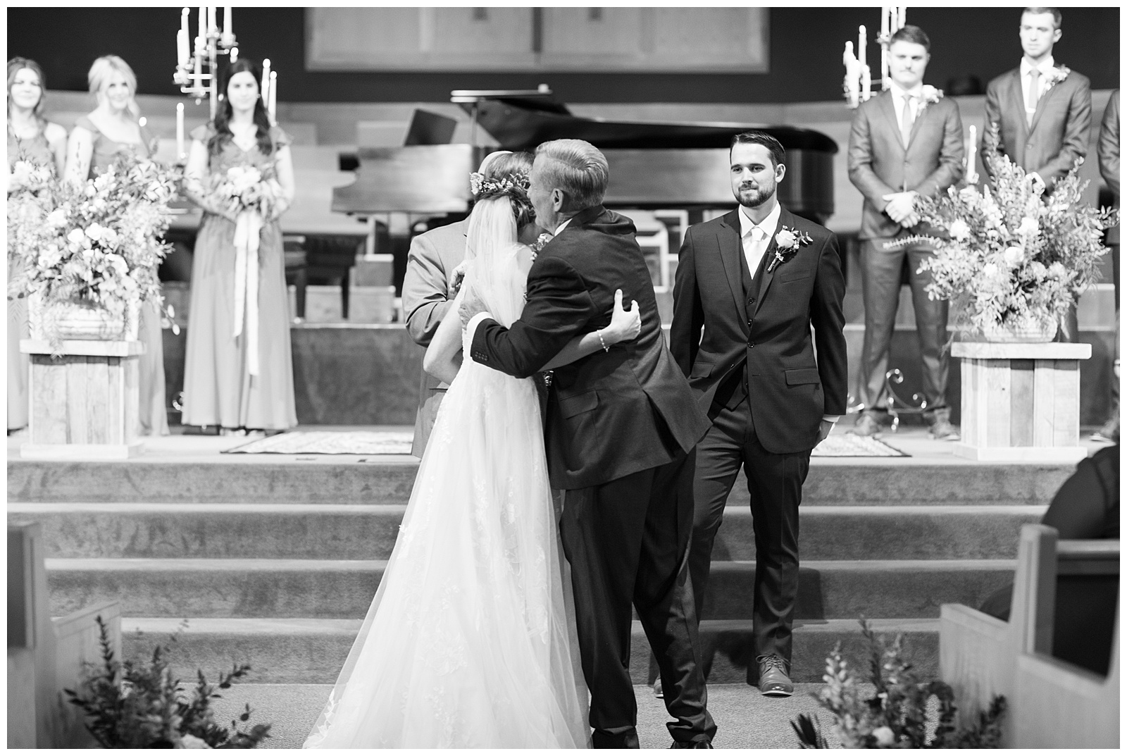 black and white image father of the bride hugging her at church wedding ceremony