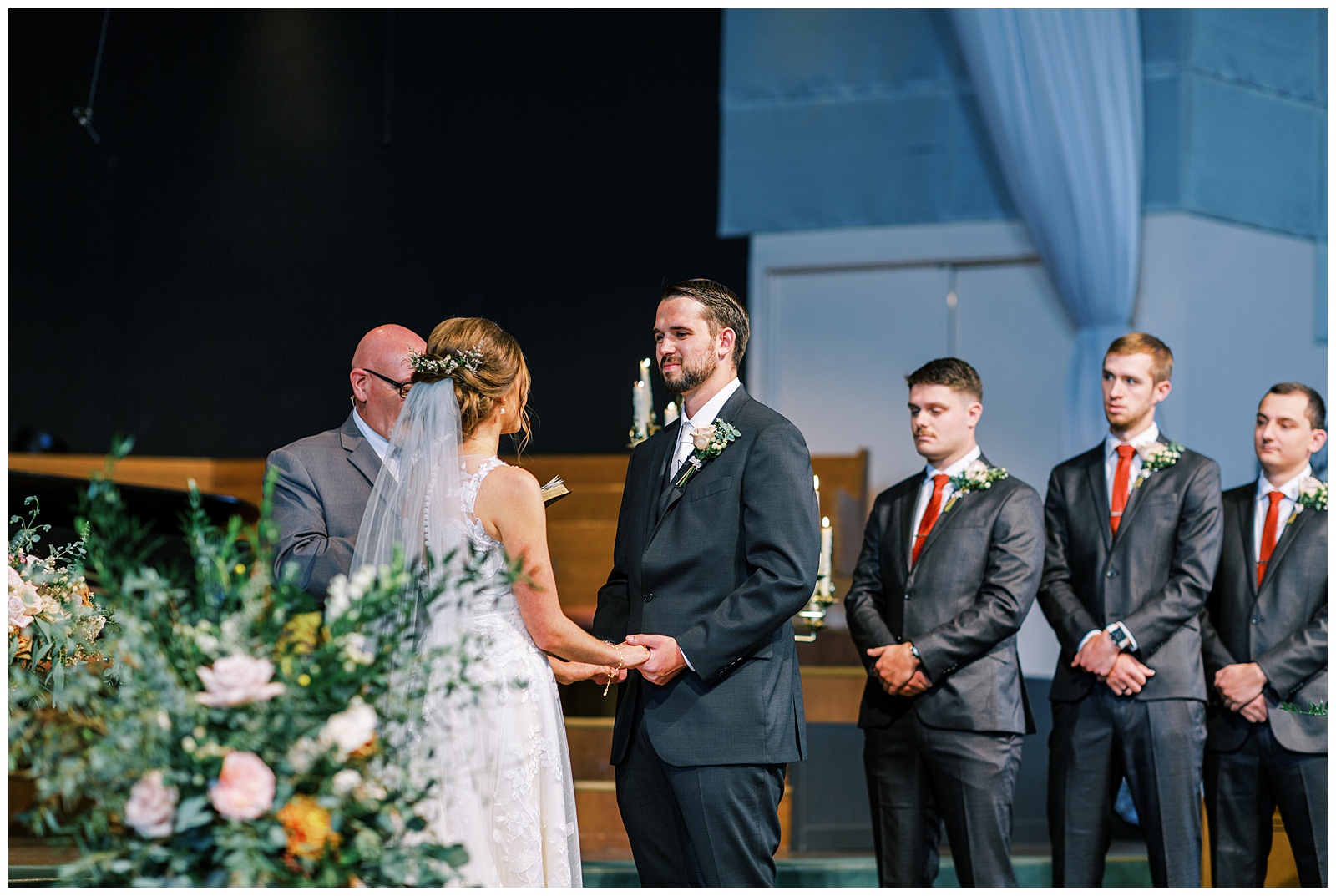 groom holding brides hands during church wedding ceremony
