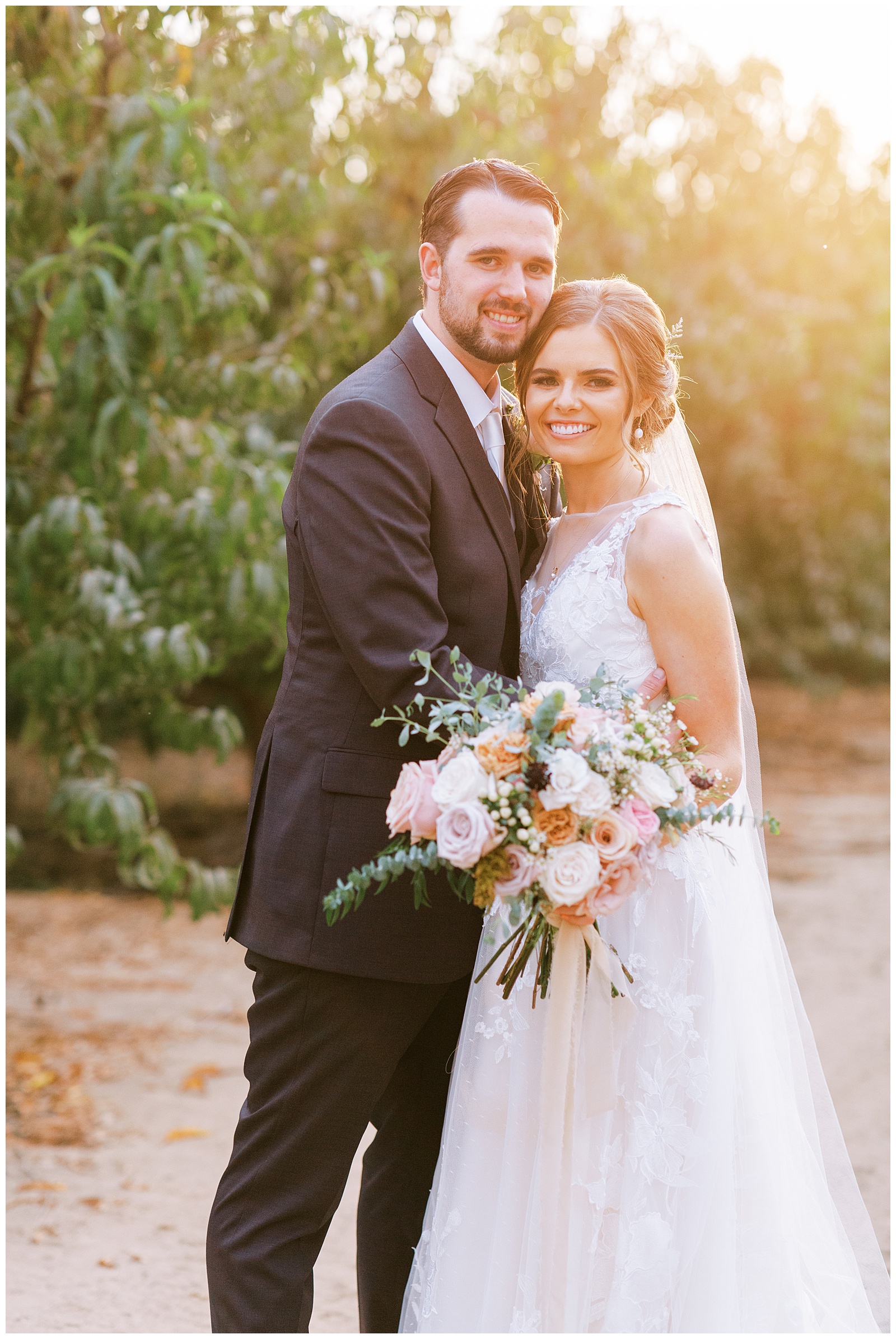 bride and groom embracing smiling at camera with golden sunlight 