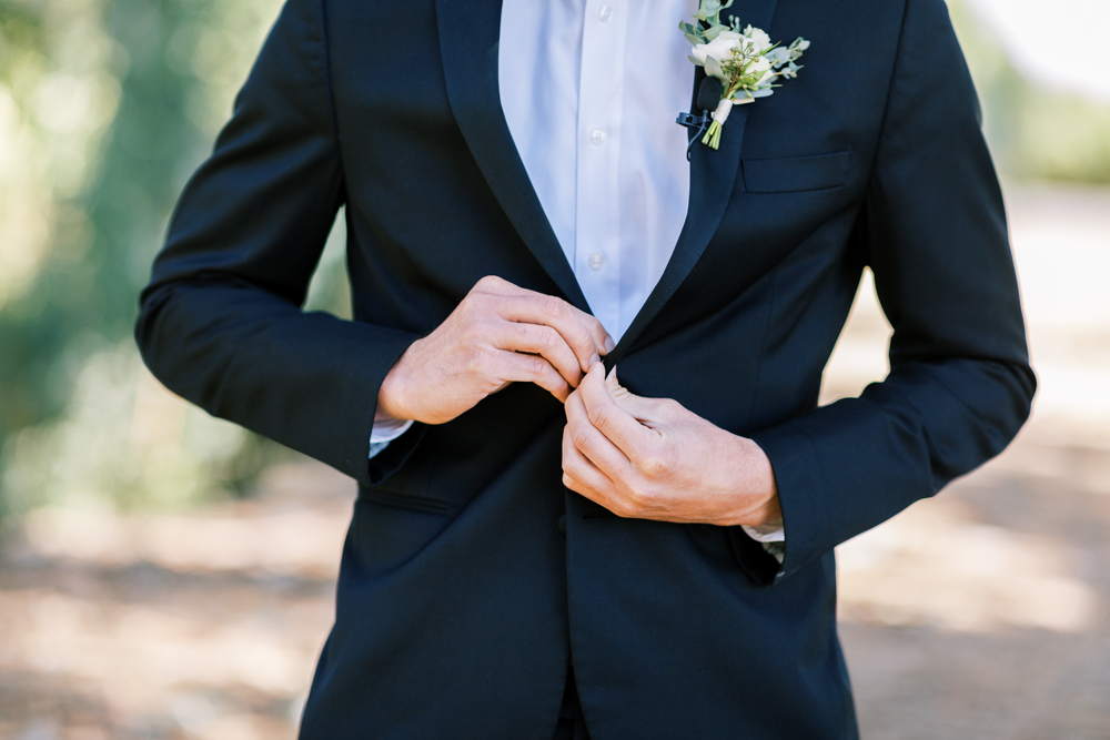 groom buttoning black suit