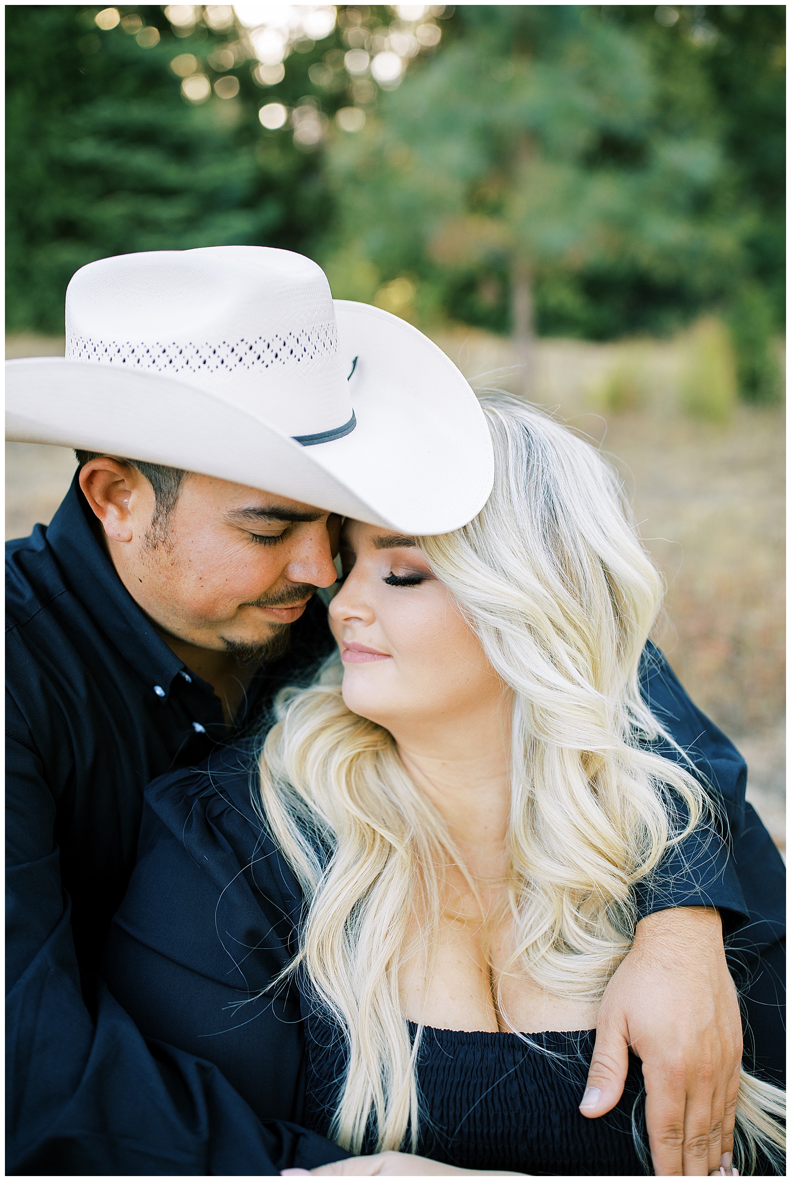 man wearing cowboy hat and black shirt hugging woman eyes closed shaver lake engagement photos