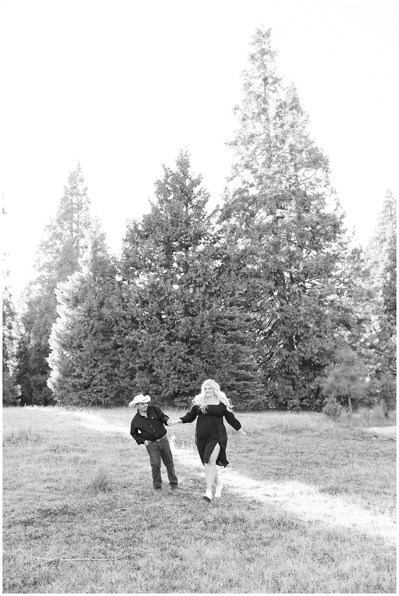 black and white image man and woman holding hands and running through grassy meadow shaver lake engagement photos