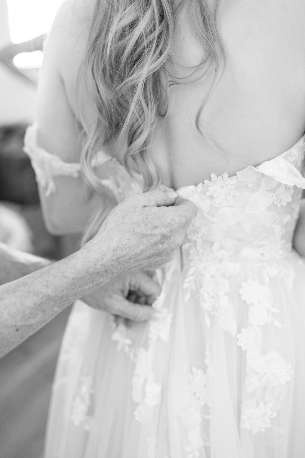 black and white photo hands zipping wedding dress