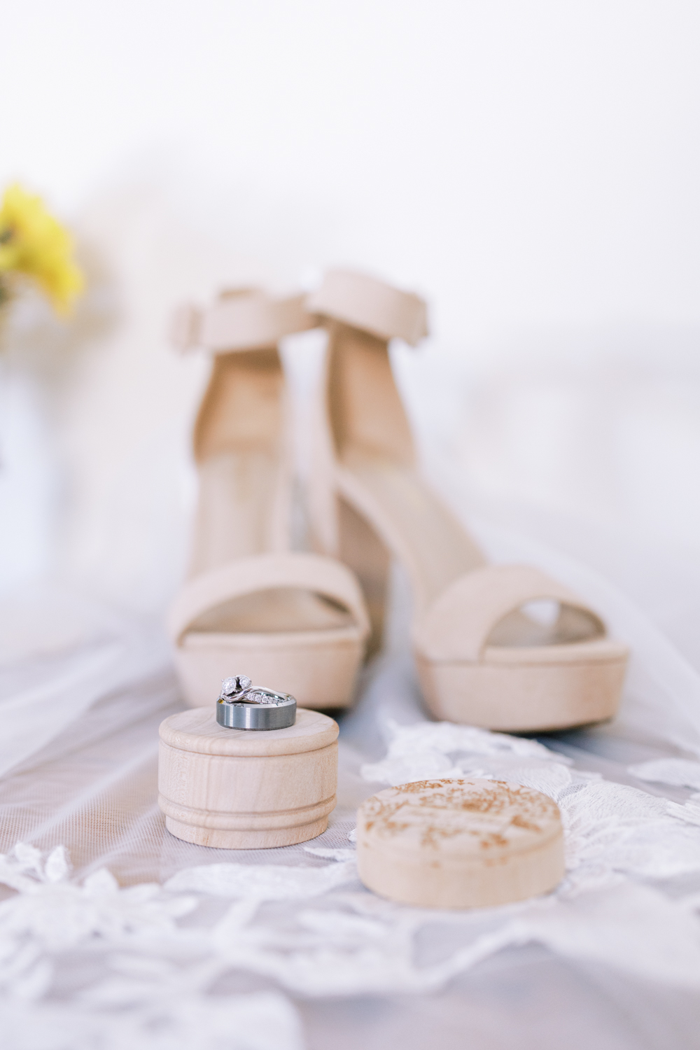 wedding rings with heels behind them and wedding veil in background