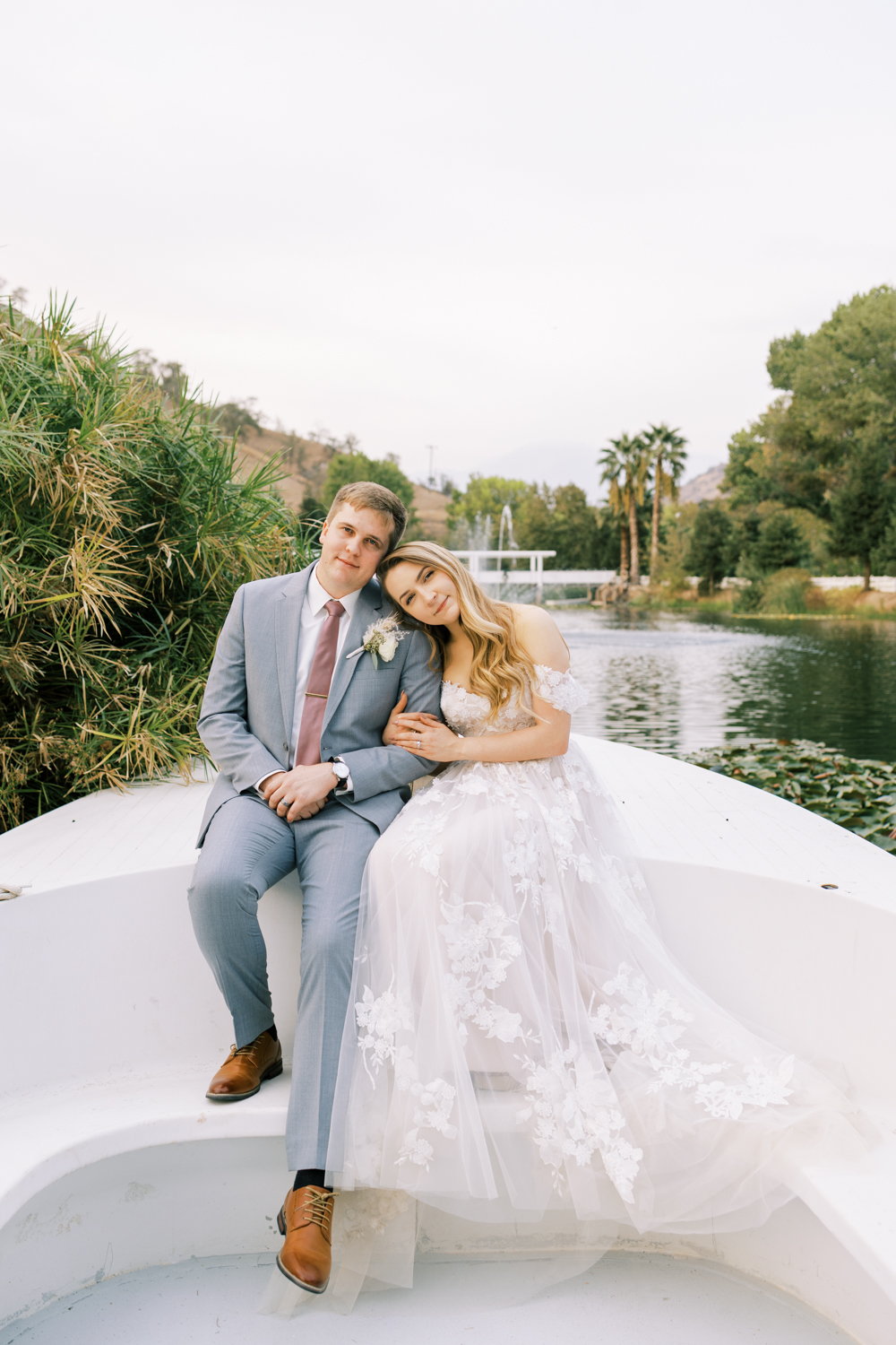 bride and groom sitting on boat by lake at springville ranch