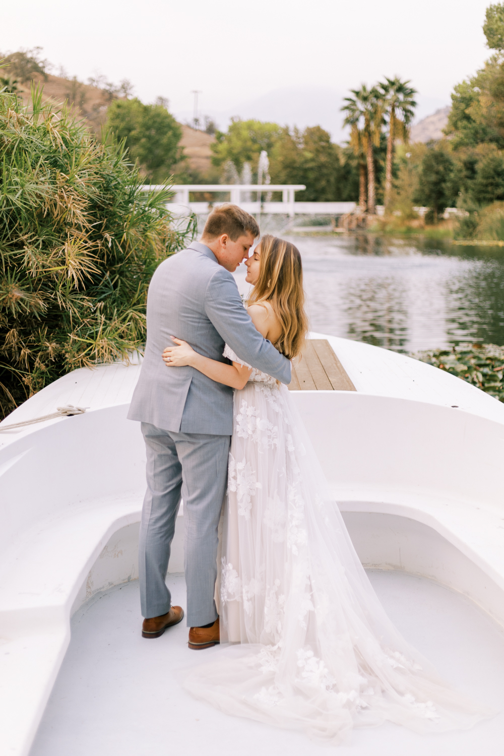 bride and groom embracing on a boat at sunset lakeside