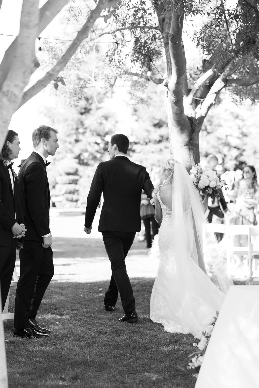 black and white photo bride and groom walking down aisle as husband and wife