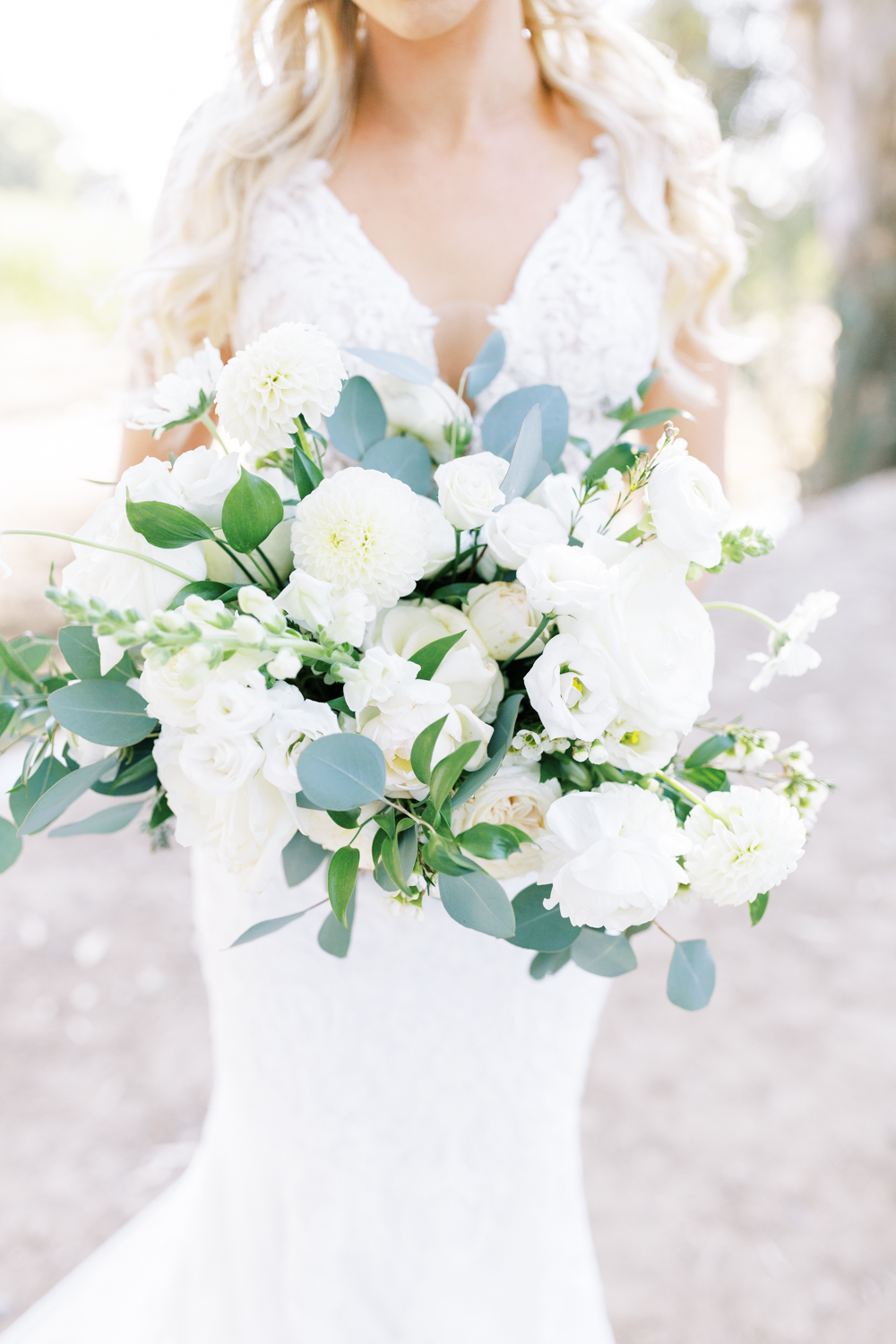 close up of white and green wedding bouquet bride holding bouquet in background