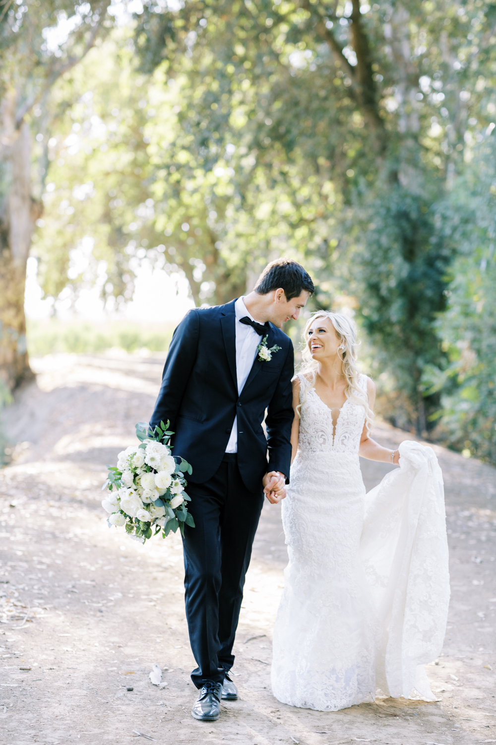 bride and groom holding hands walking and smiling groom holding bouquet