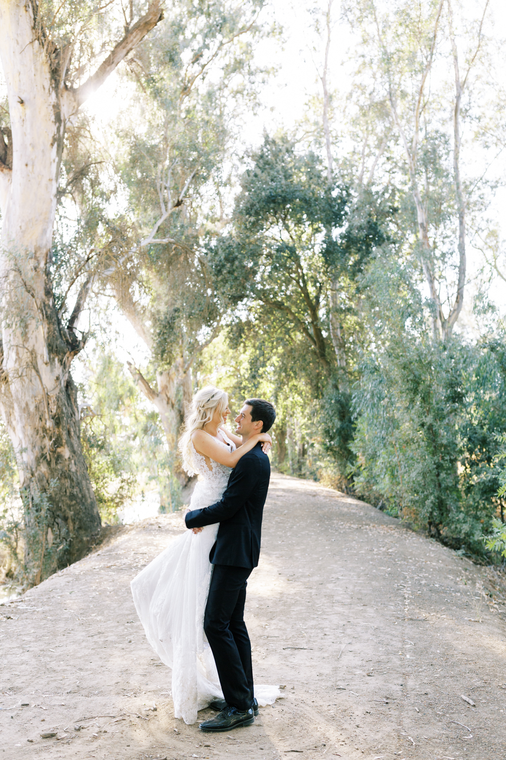 groom picking up bride on eucalyptus lined drive