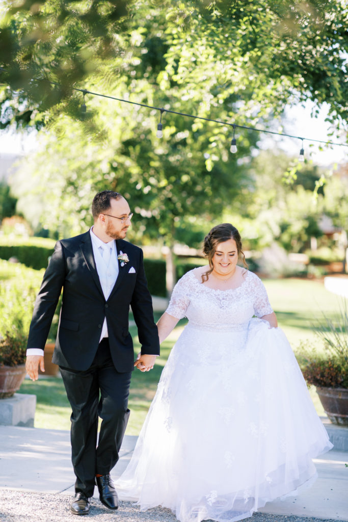 bride and groom holding hands walking into wedding reception at the gardens venue in tulare california
