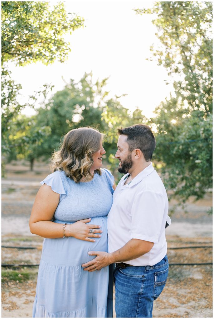 husband and wife looking at each other and smiling during maternity photos