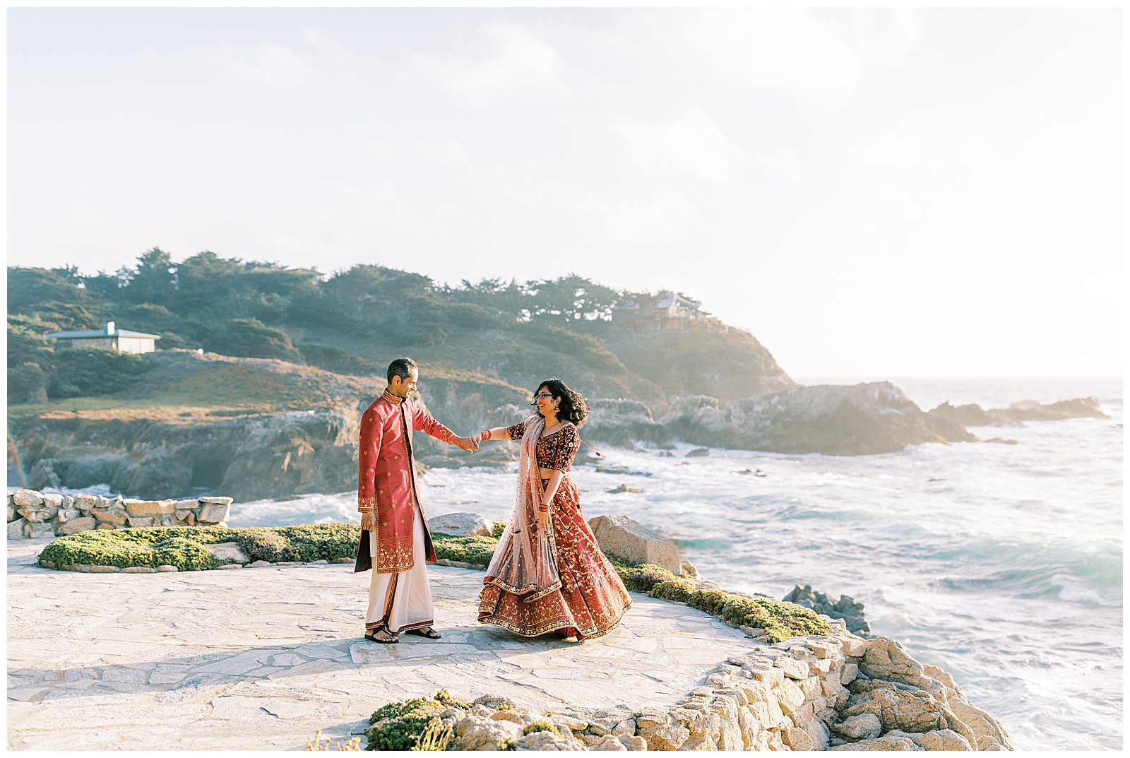bride and groom dancing in traditional indian wedding attire on cliffside in carmel-by-the-sea california