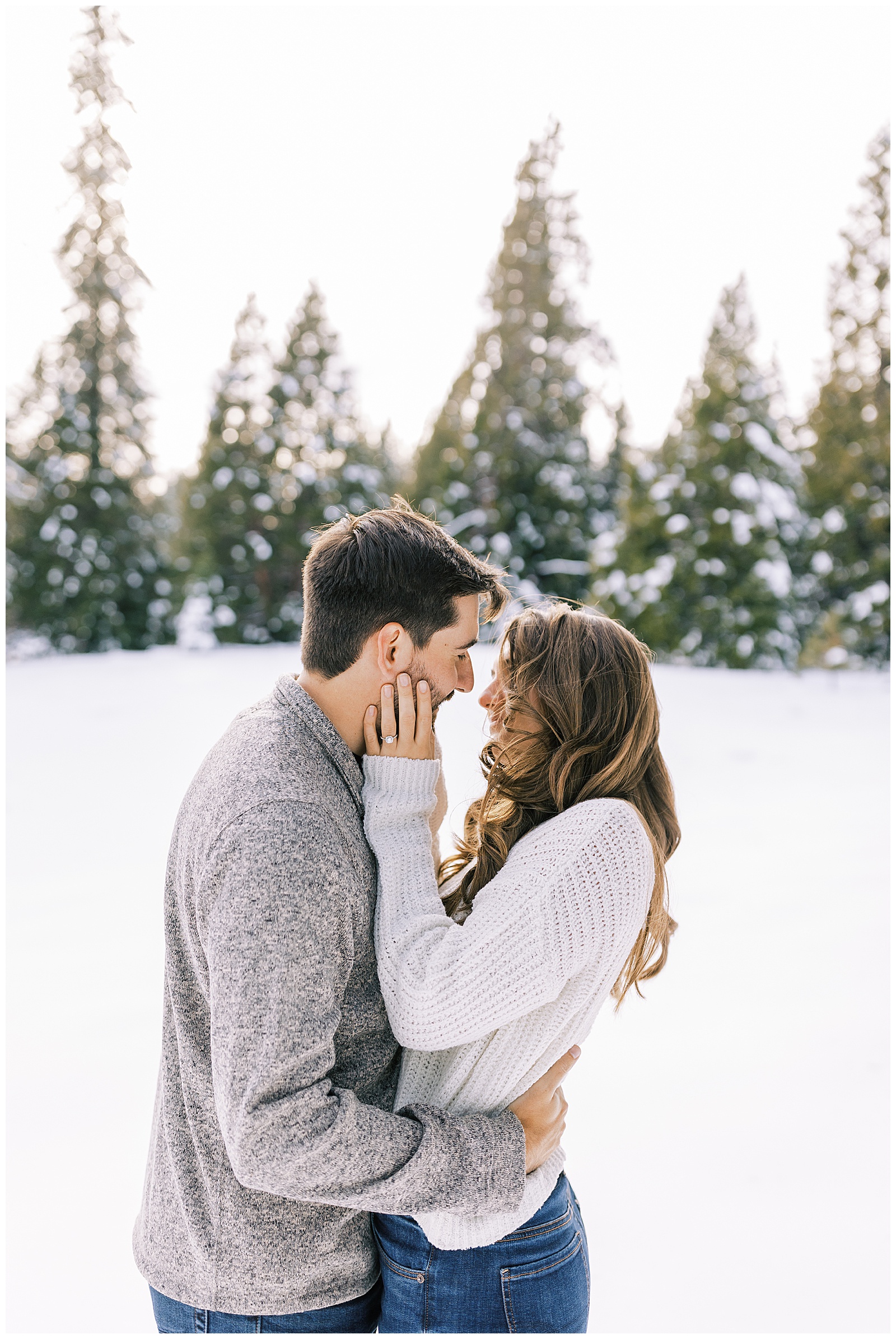 engaged couple wearing neutral sweaters snowy winter engagement photos