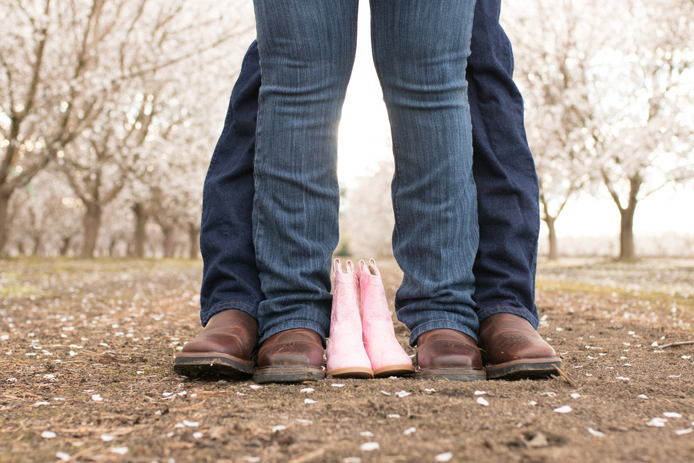 photo of a couple standing with baby shoes for a maternity session
