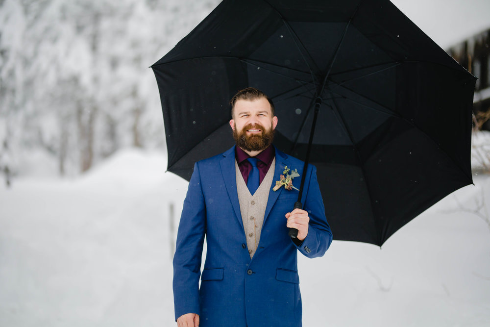 groom standing in the snow waiting for the first look