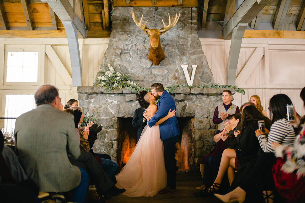 wedding kiss by the fireside at an indoor winter wedding ceremony