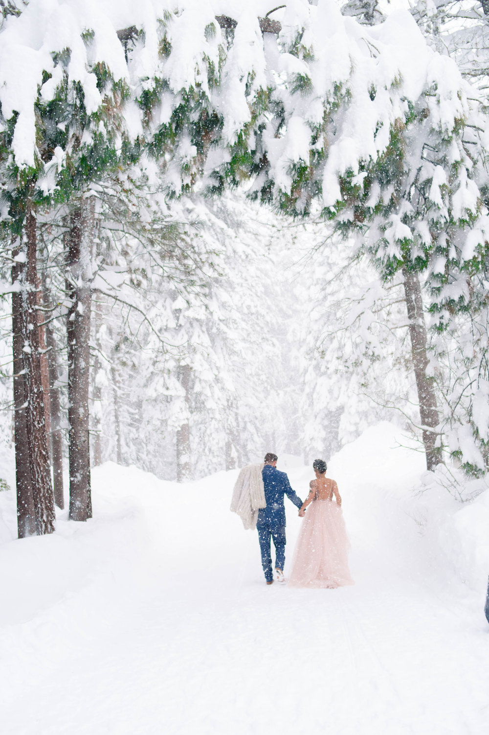 bride and groom walking for their snowy wedding photos