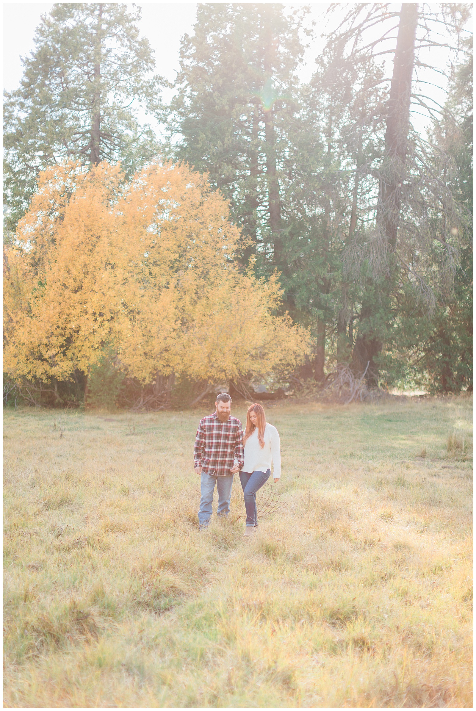 couple walking through a meadow in the fall for engagement photos