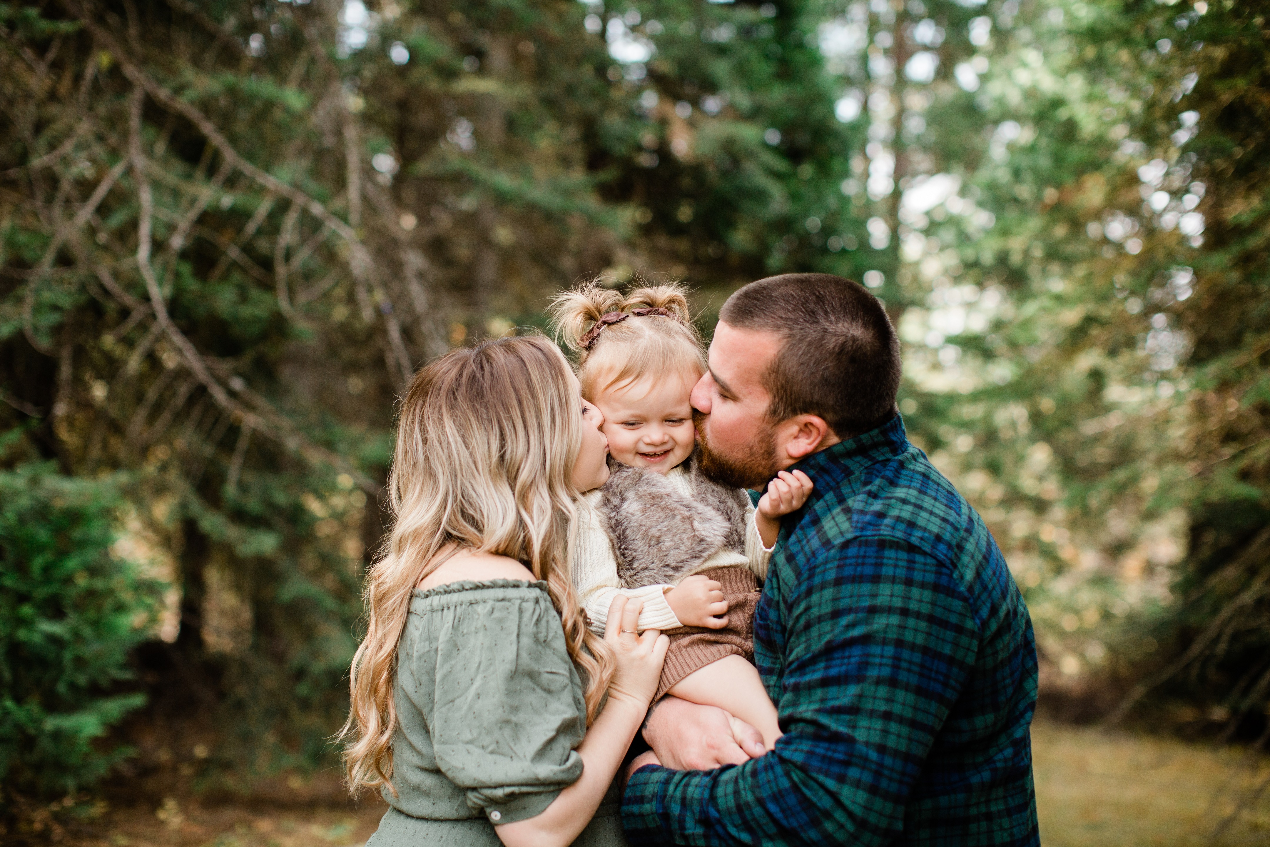 mom and dad kissing their kid during a fall family photo session in shaver lake ca
