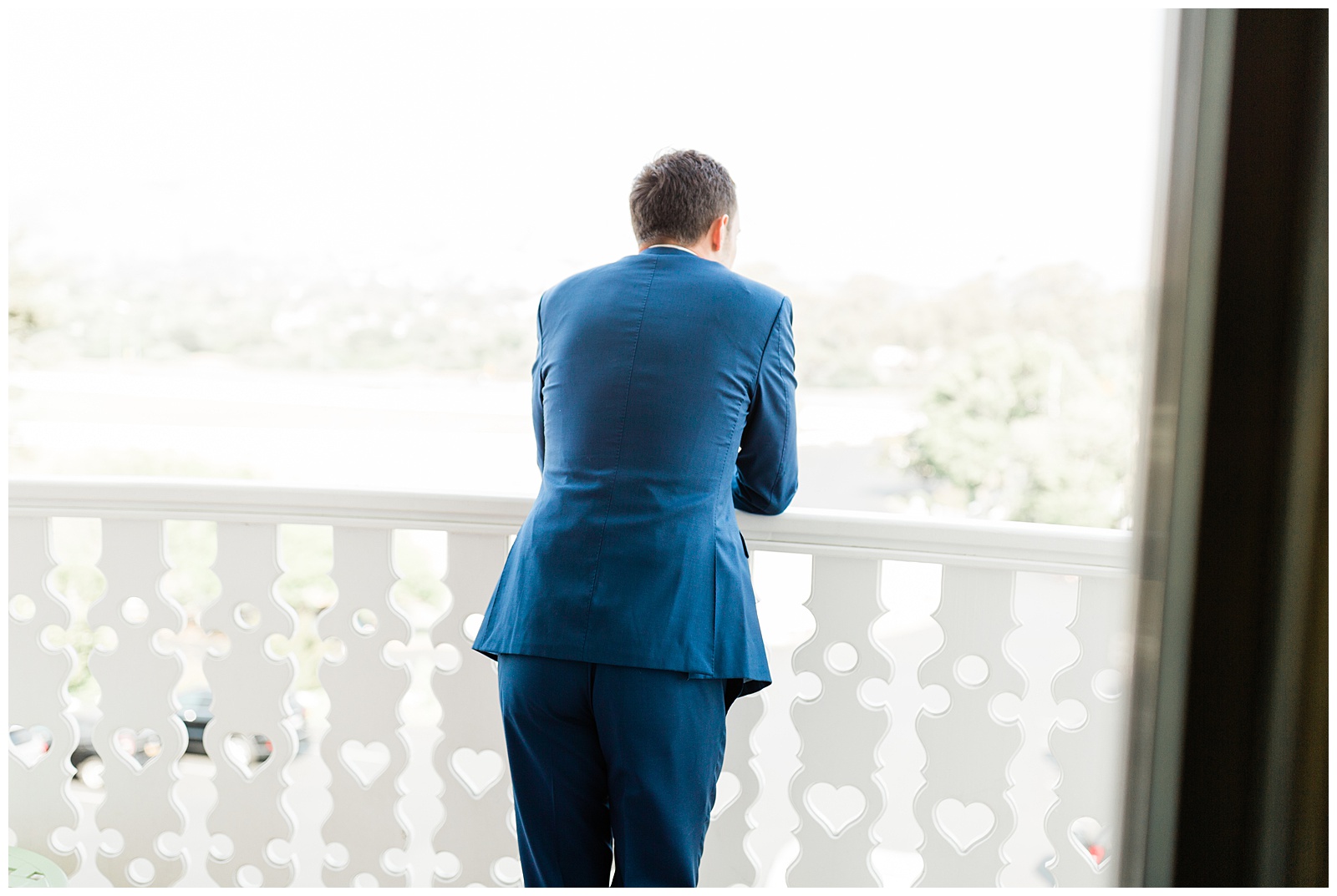 A groom waiting for the first look with his bride on the balcony of the Madonna Inn in San Luis Obispo