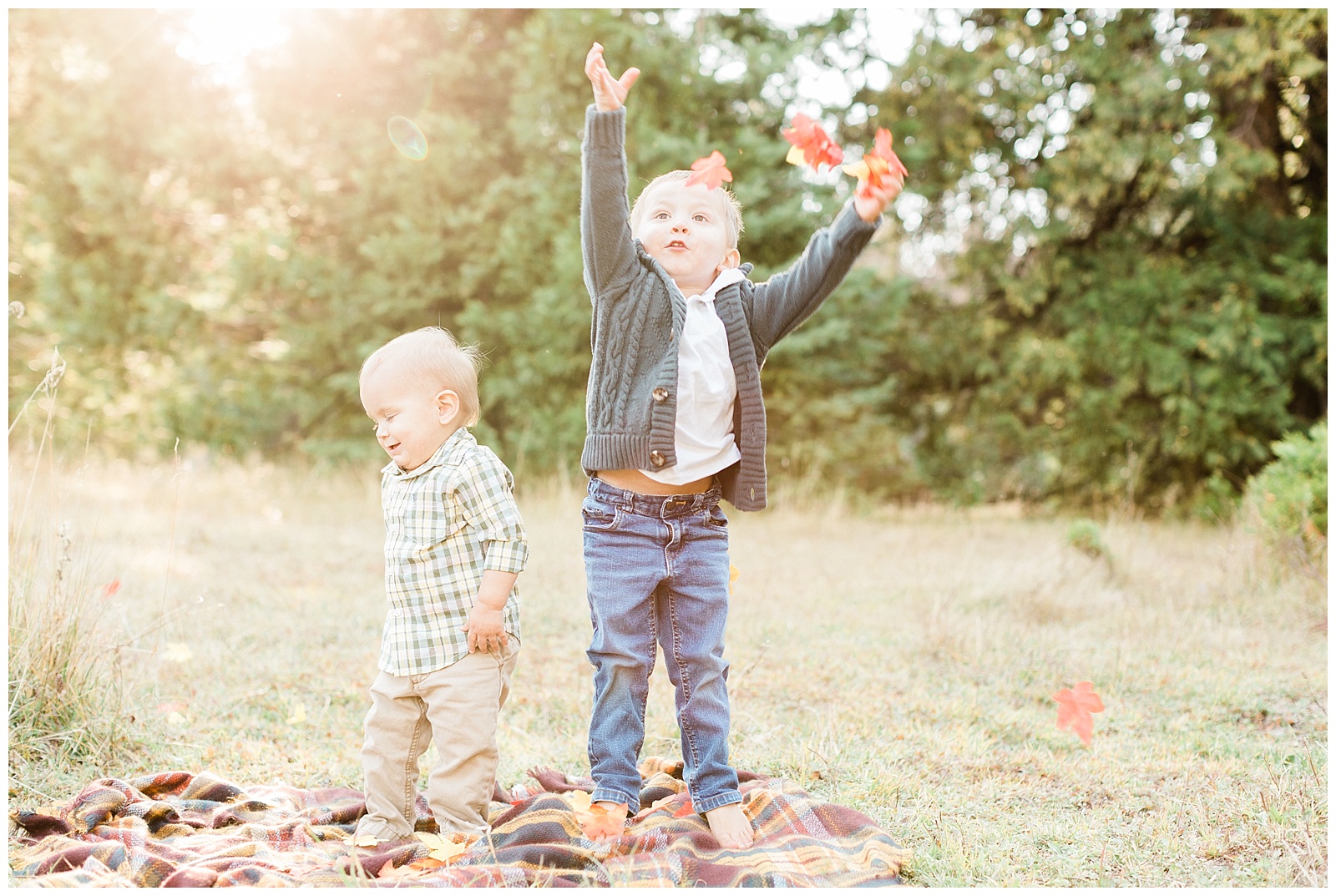 young boys throwing fall leaves up in the air