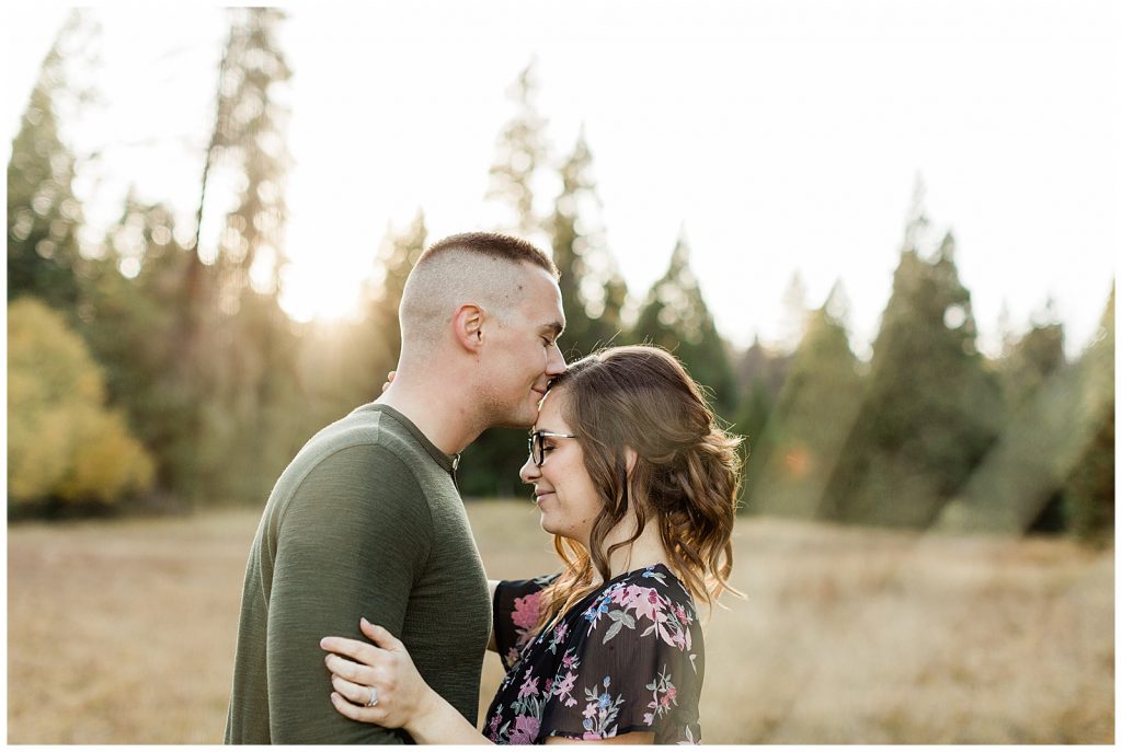 man kissing his finace on the forehead during fall engagement photos at sunset in the mountains