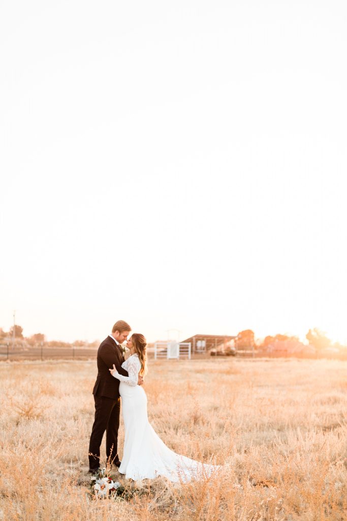 newlyweds standing in an open field at sunset for a winter Christmas wedding