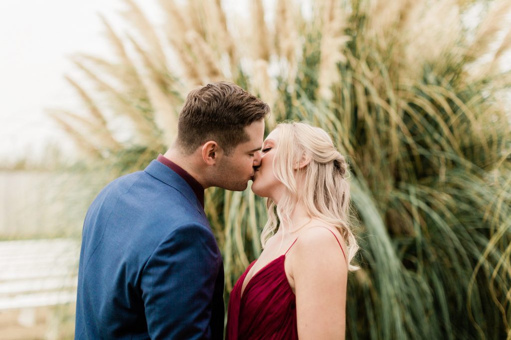 couple kissing in front of a pampas grass bush