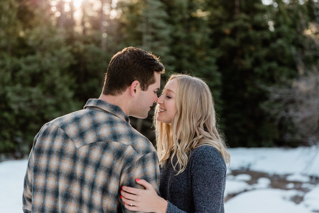 sweet nose to nose picture of couple with pine trees in back