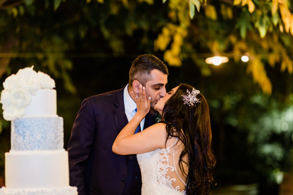 bride and groom kissing near wedding cake