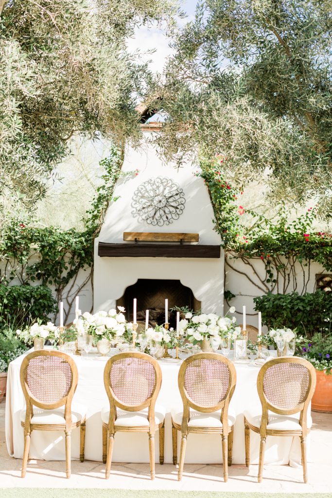 outdoor reception table with blush and wood chairs and white centerpieces