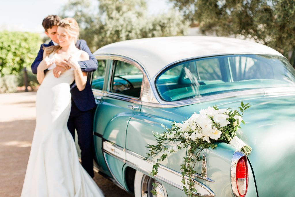 bride and groom hugging in front teal vintage car