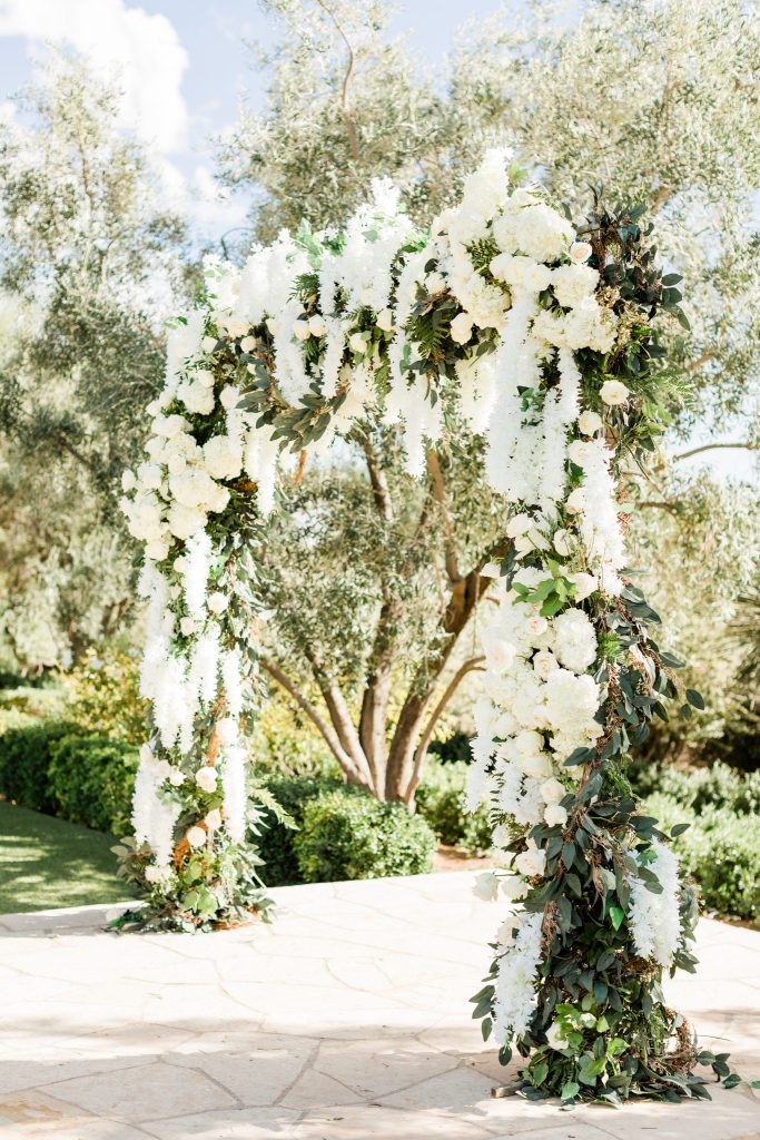 white floral arch with roses and draped flowers