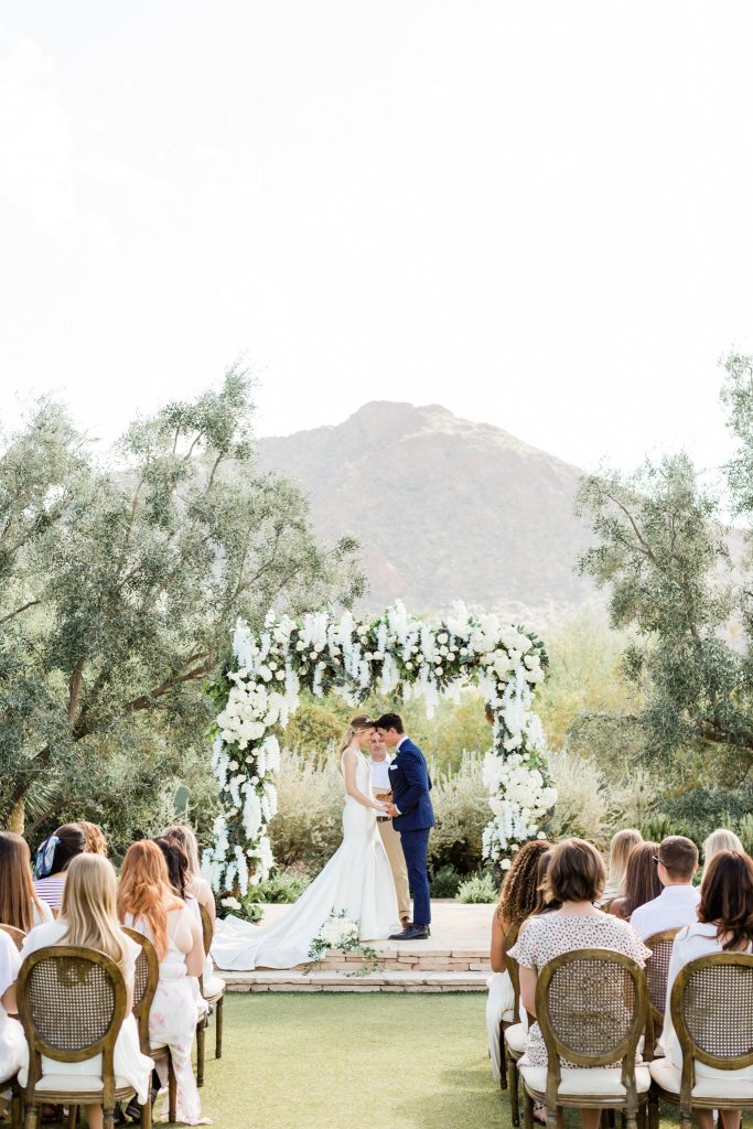 outdoor ceremony with white flower covered arch
