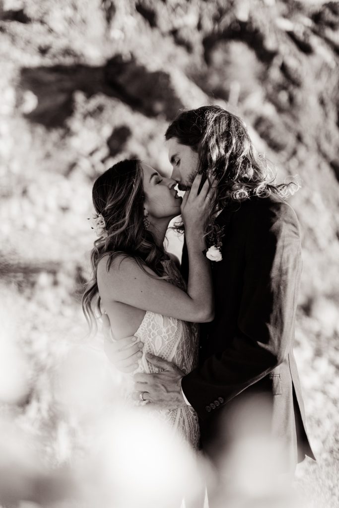 black and white portrait of a bride and groom about to kiss in the desert