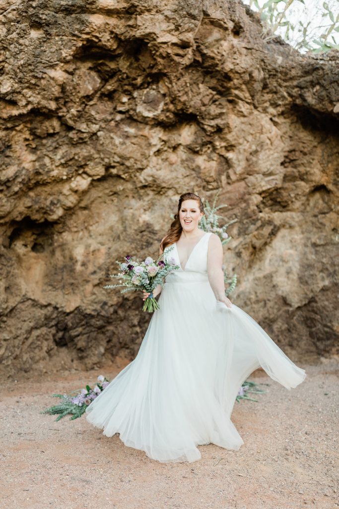 red headed bride holding a lavender bouquet and twirling in a simple white wedding gown