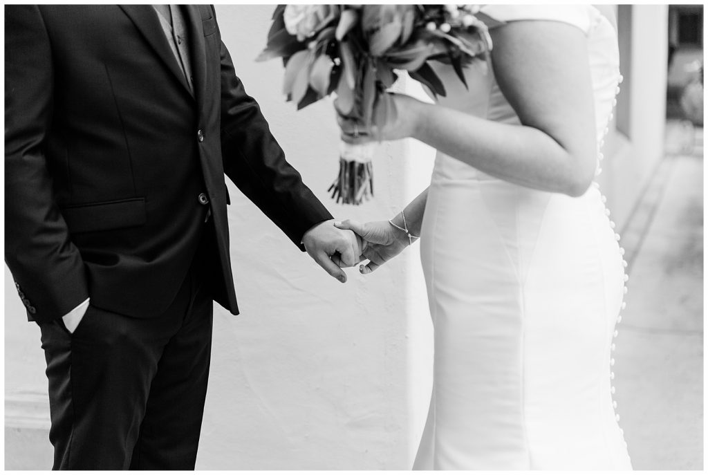 black and white detail image of bride and groom holding hands during first look