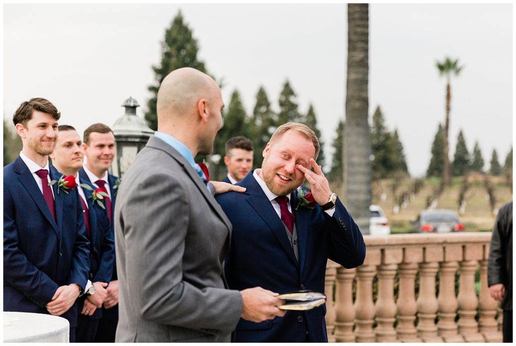 groom in navy suit tearfully awaiting his bride