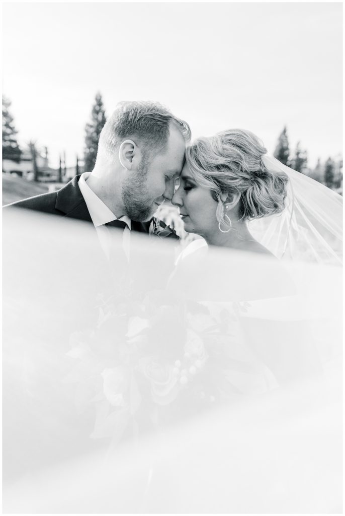black and white romantic image of couple behind veil