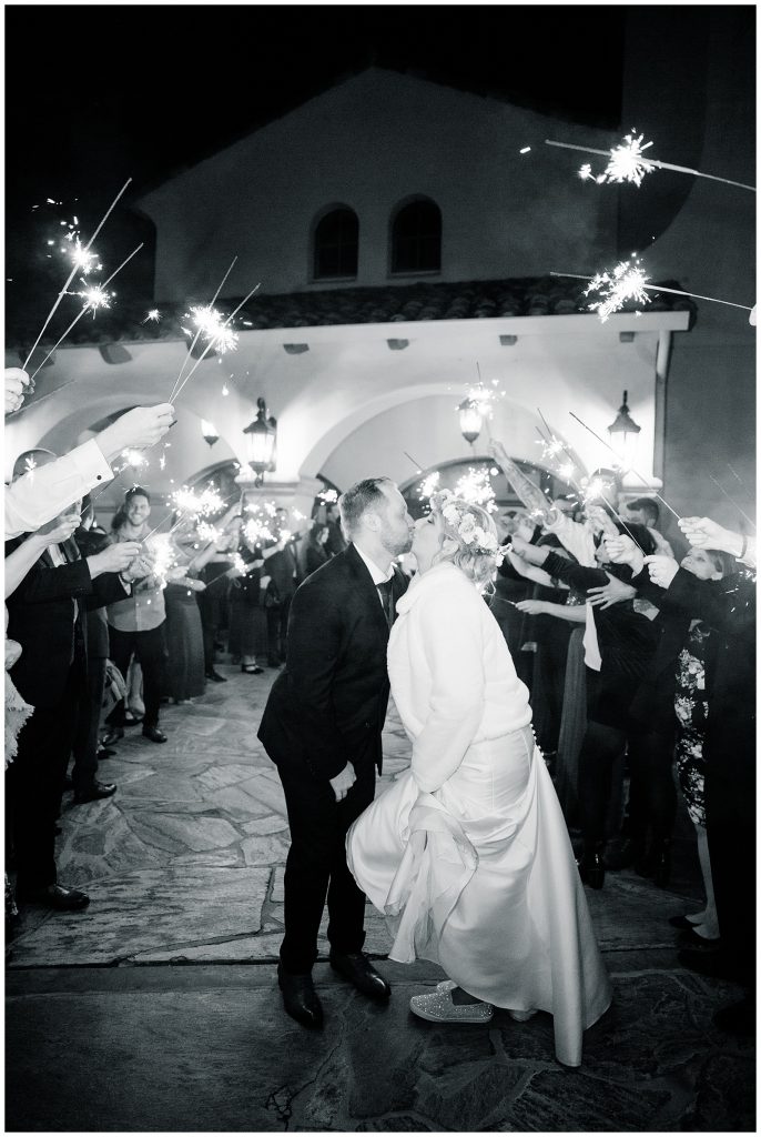 black and white photo kissing during sparkler exit