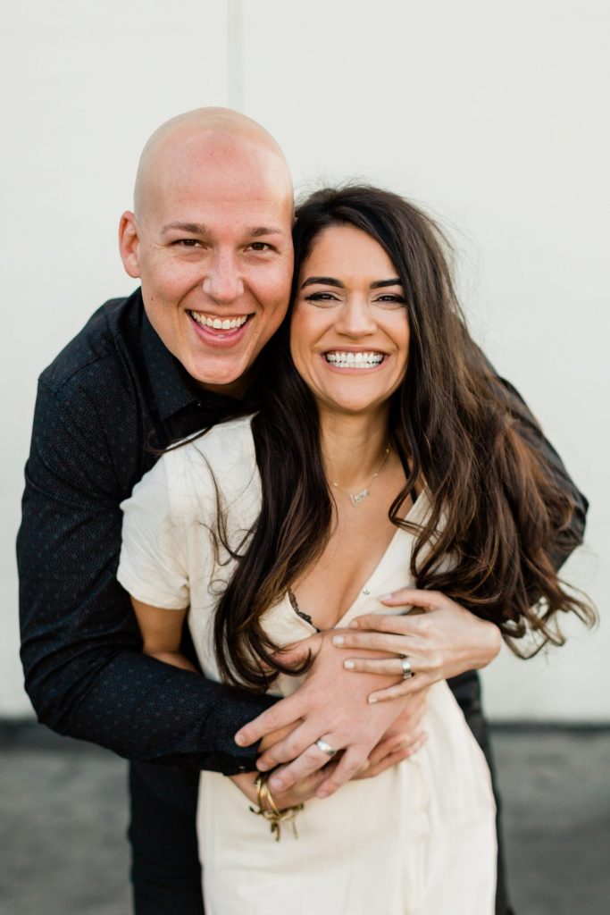 man hugging his wife while they both smile