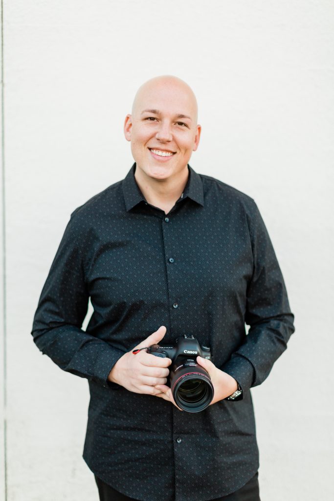 man smiling and holding a camera