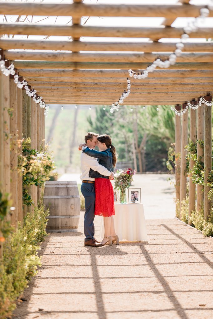 couple standing nose to nose in an intimate embrace under a wooden archway