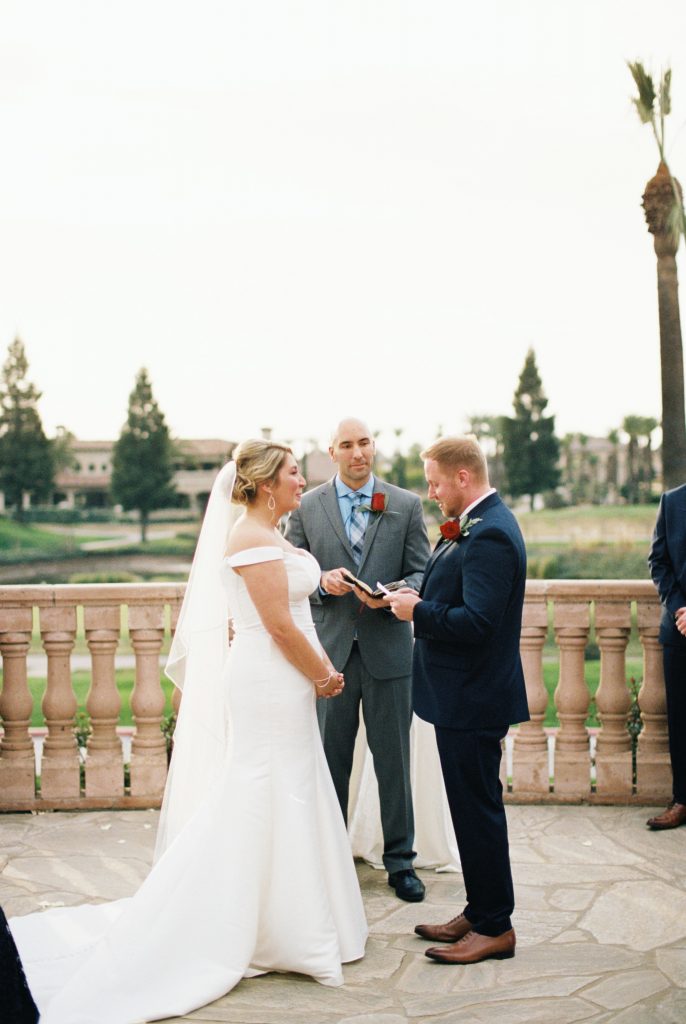 Groom in navy suit reading vows to bride